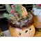 This shows the greenery decorating the elf hat. It is nestled together with, jingle bells, pinecones, and the faux fur trim around the hat.